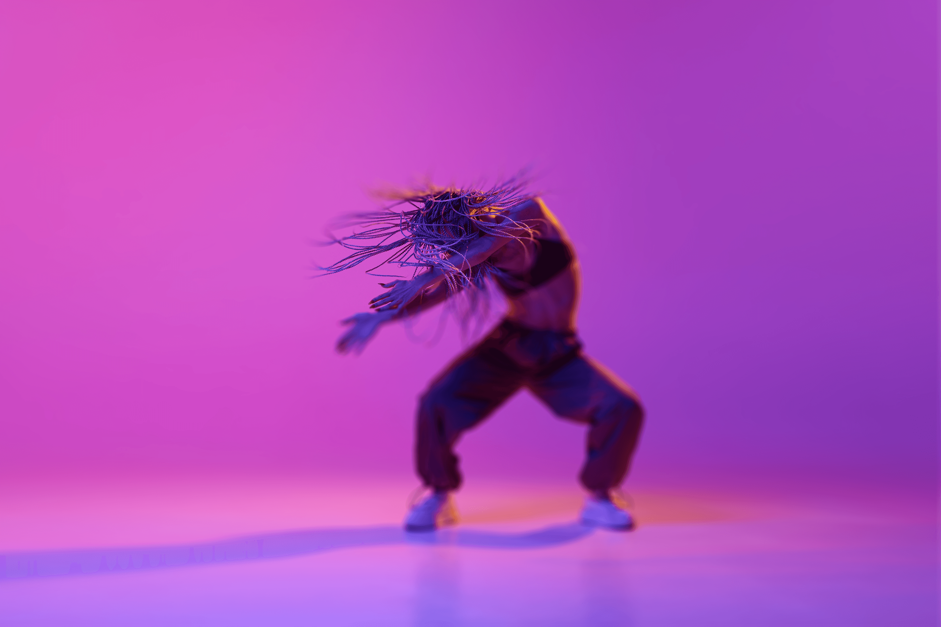 A silhouette of a person is captured in dynamic motion against a vibrant purple background, with intricate, light-reflective wires obscuring their face, adding a surreal touch to their dance pose.